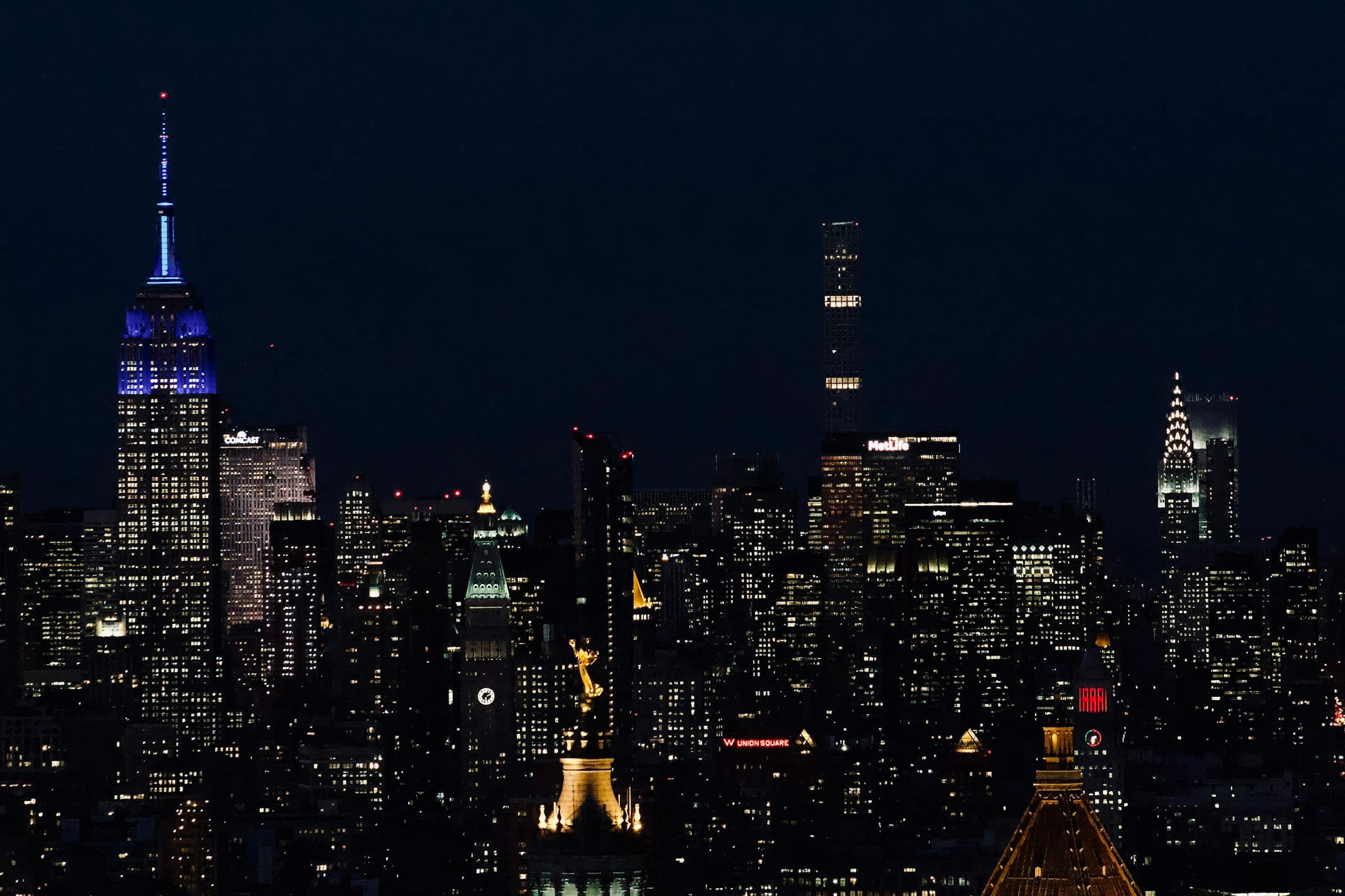 Midtown Manhattan just after dusk: the Empire State Building and the Chrysler Building lit against a dark sky.